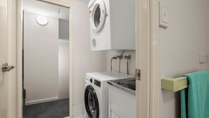 A laundry room with a washing machine, dryer, and a towel rack.