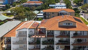 A multi-story residential building with a red-tiled roof, balconies, and a visible garage.