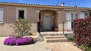 A two-story building with a beige facade, a white door, and a small porch with steps leading to the entrance. - A single-storey house in a quiet subdivision with swimming pool and parking. (Manduel)