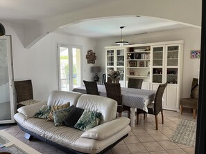 Ein Wohnzimmer mit einer Couch, einem Esstisch, Stühlen und einem Bücherregal.