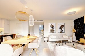 Ein modernes Wohnzimmer mit Essbereich, weißen Möbeln und Kunstwerken an den Wänden.