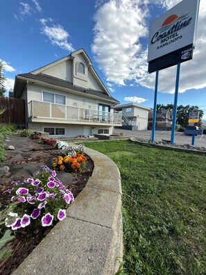 A motel with a signboard, a balcony, and a flower bed.
