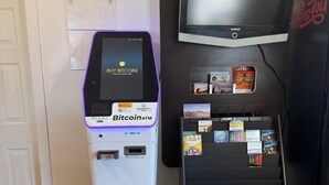 Un cajero automático de Bitcoin, un televisor Samsung y un quiosco de información turística en un vestíbulo.