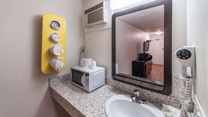 Un baño con lavamanos, espejo y un toallero amarillo con toallas.