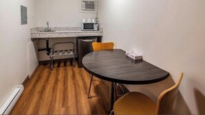 Una habitación pequeña con una mesa redonda, un microondas y una silla.