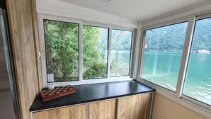 A kitchen with a view of a lake and forest, a wooden cabinet, and a chessboard. - Lake House Perucac (Rađenovići)