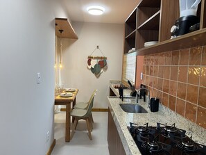 Eine Küche mit Essbereich, einem Gasherd, einer Spüle und einem Fenster mit Jalousien.