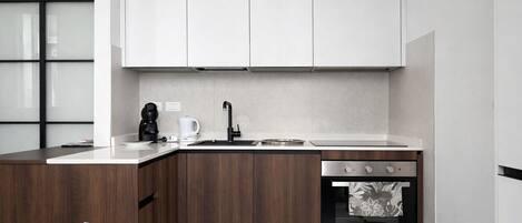 Una cocina moderna con armarios de madera, un lavamanos de acero inoxidable y un horno empotrado.