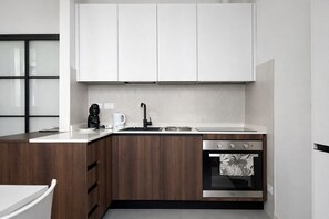 A modern kitchen with wooden cabinets, a stainless steel sink, and a built-in oven. - TATI HOME - two-room apartment in the center 1 minute from piazza unità (Trieste)