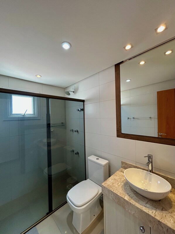 Une salle de bain moderne avec une douche à parois de verre, des toilettes, un lavabo et un grand miroir.