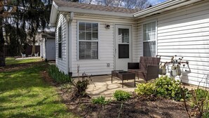A single-story house with a patio area, outdoor furniture, and a small garden.
