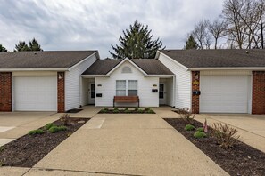 A two-story building with a central entrance, two garages, and a bench in front.