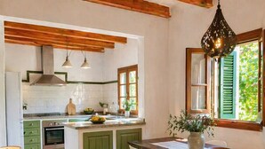 A kitchen with green cabinets, a wooden dining table, and a hanging light fixture. - Can Gallardo d'en Fuster by Mallorca North Villas (Pollensa / Pollença)