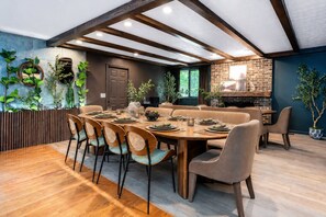 A dining area with a long wooden table set for six, surrounded by cushioned chairs.
