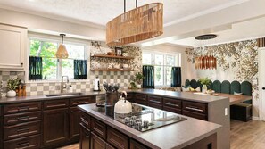 A modern kitchen with dark wood cabinets, a central island, and a hanging light fixture. - Stunning, Fully Loaded Massanutten 8BR Home! Sleeps 20 (McGaheysville)