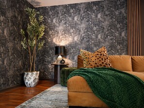 A modern living room with a sofa, a lamp, a potted plant, and a textured wall. - Stunning, Fully Loaded Massanutten 8BR Home! Sleeps 20 (McGaheysville)