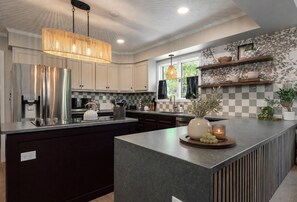 A modern kitchen with a central island, stainless steel appliances, and a pendant light.