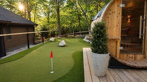 A wooden cabin with a deck, a small lawn with a flag, and a large potted plant. - Stunning, Fully Loaded Massanutten 8BR Home! Sleeps 20 (McGaheysville)