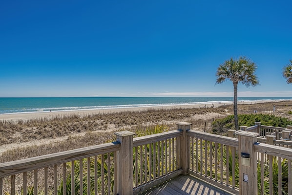 A wooden deck overlooking a beach with a clear sky. - Spacious Home in Ocean Lakes. Outdoor entertainment, and Gated covered deck. (Myrtle Beach)