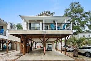 A two-story building with a covered balcony, a sign indicating a restaurant, and a vehicle parked in front. - Spacious Home in Ocean Lakes. Outdoor entertainment, and Gated covered deck. (Myrtle Beach)