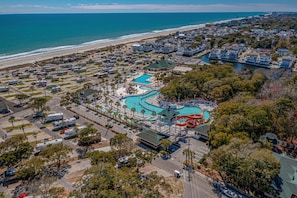 An aerial view of a coastal resort with a large swimming pool, RV parking, and beachfront properties. - Spacious Home in Ocean Lakes. Outdoor entertainment, and Gated covered deck. (Myrtle Beach)