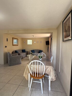 A dining area with a table, chairs, and a sofa. - Affordable and spacious  2BR/2BA Close to Airport & South Coast (sleeps 4) (Oistins)