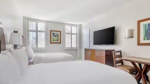 Ein Hotelzimmer mit zwei Betten, einem Fernseher, einem Schreibtisch und einer Kommode.