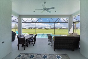 Un patio cubierto con piscina, mobiliario de exterior y vistas a una zona residencial.