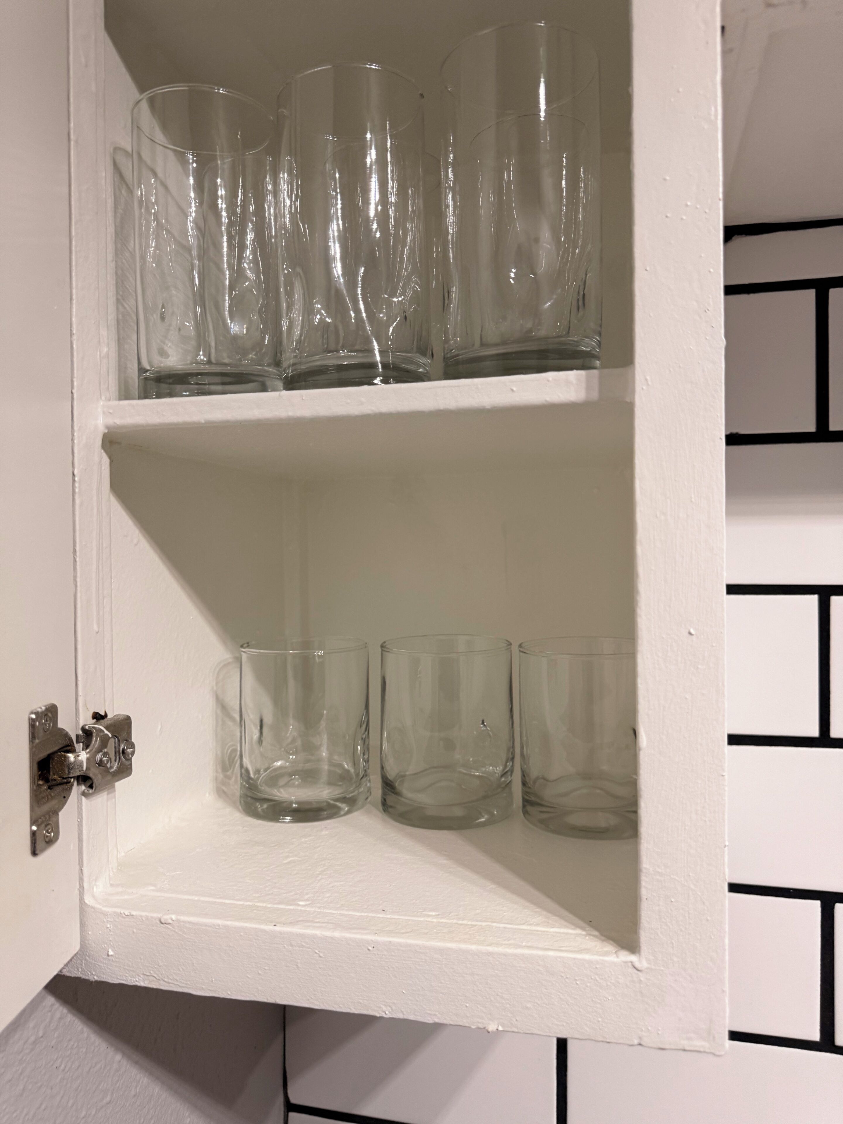 Un meuble blanc à deux étagères contenant de la verrerie transparente.