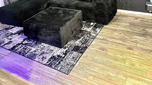 Una sala de estar moderna con un sofá modular, un tapete estampado y tres cuadros en la pared.