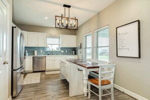 A kitchen with white cabinets, a stainless steel refrigerator, a dishwasher, a wooden island table, and a framed thank you sign. - Family Beach House Just Steps From The Sand (Surfside Beach)