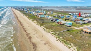 Zona residencial costera con casas a lo largo de la playa, un tanque de agua y una flecha roja que indica una vivienda específica.
