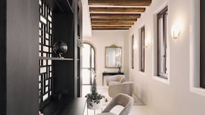 Un pasillo con un aparador de madera oscura, un globo terráqueo y dos sillones tapizados.