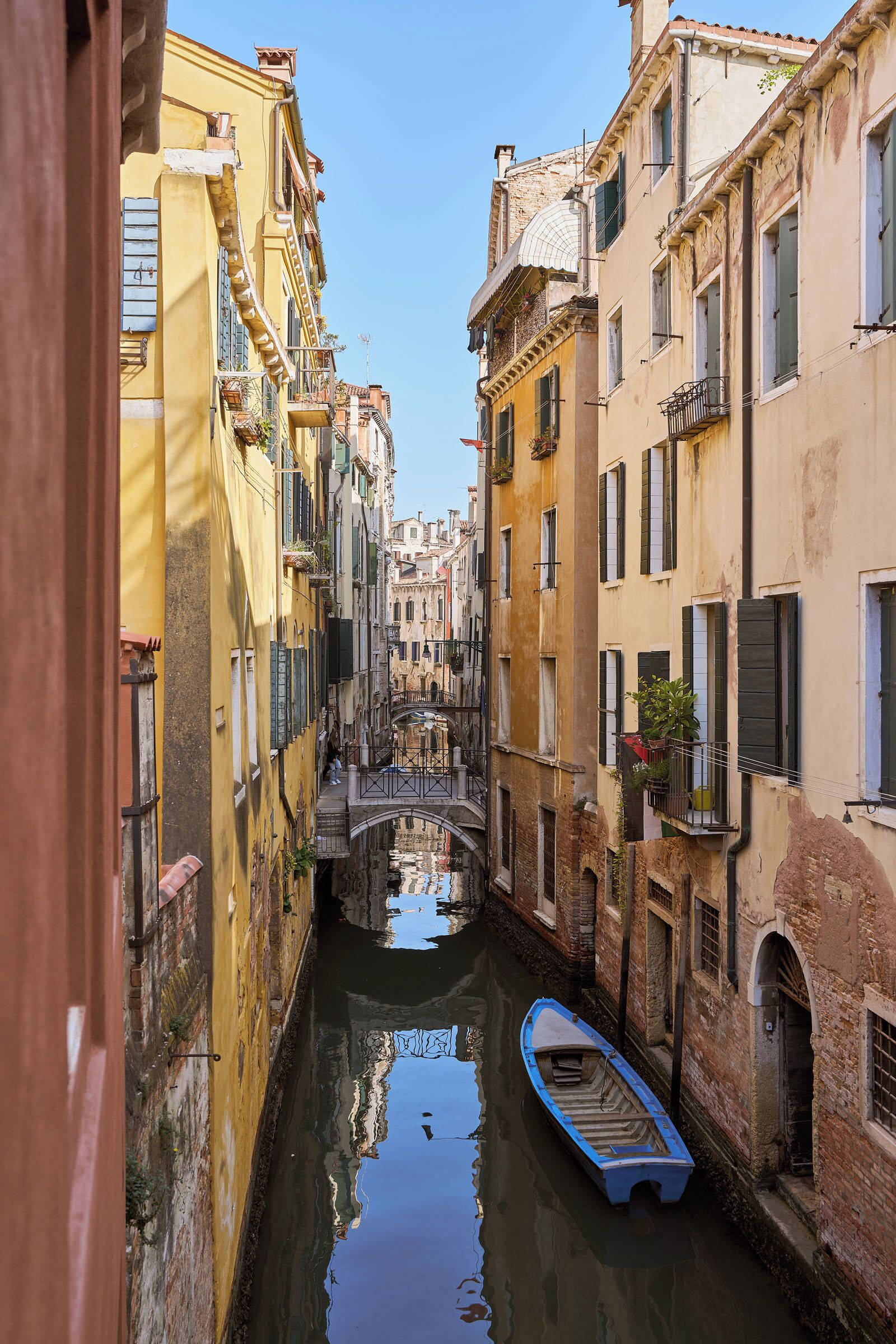 A narrow canal flanked by historic buildings with a boat docked on the water.
