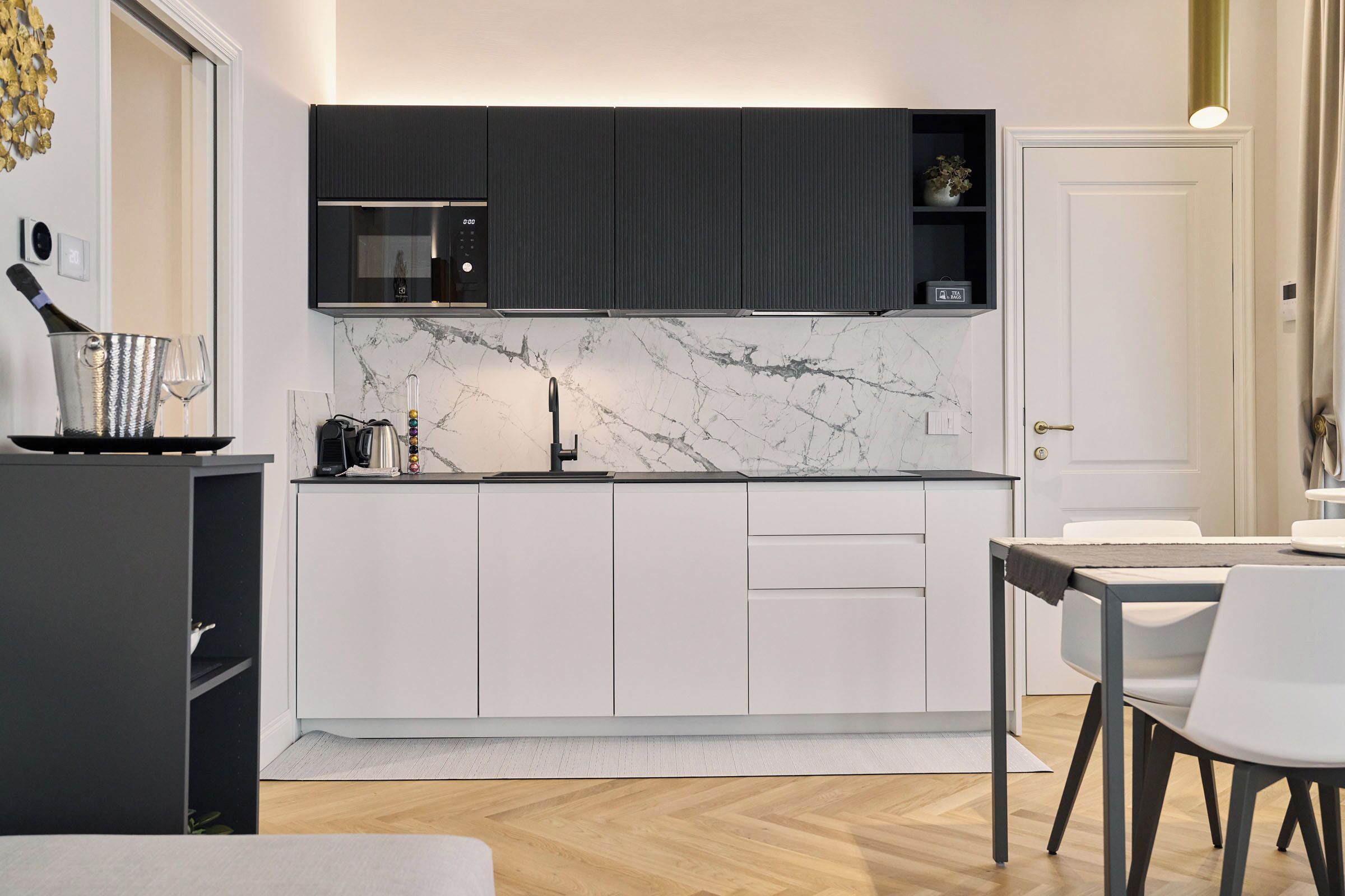 A modern kitchen with white cabinets, a marble backsplash, and a dining area with a table and chairs.