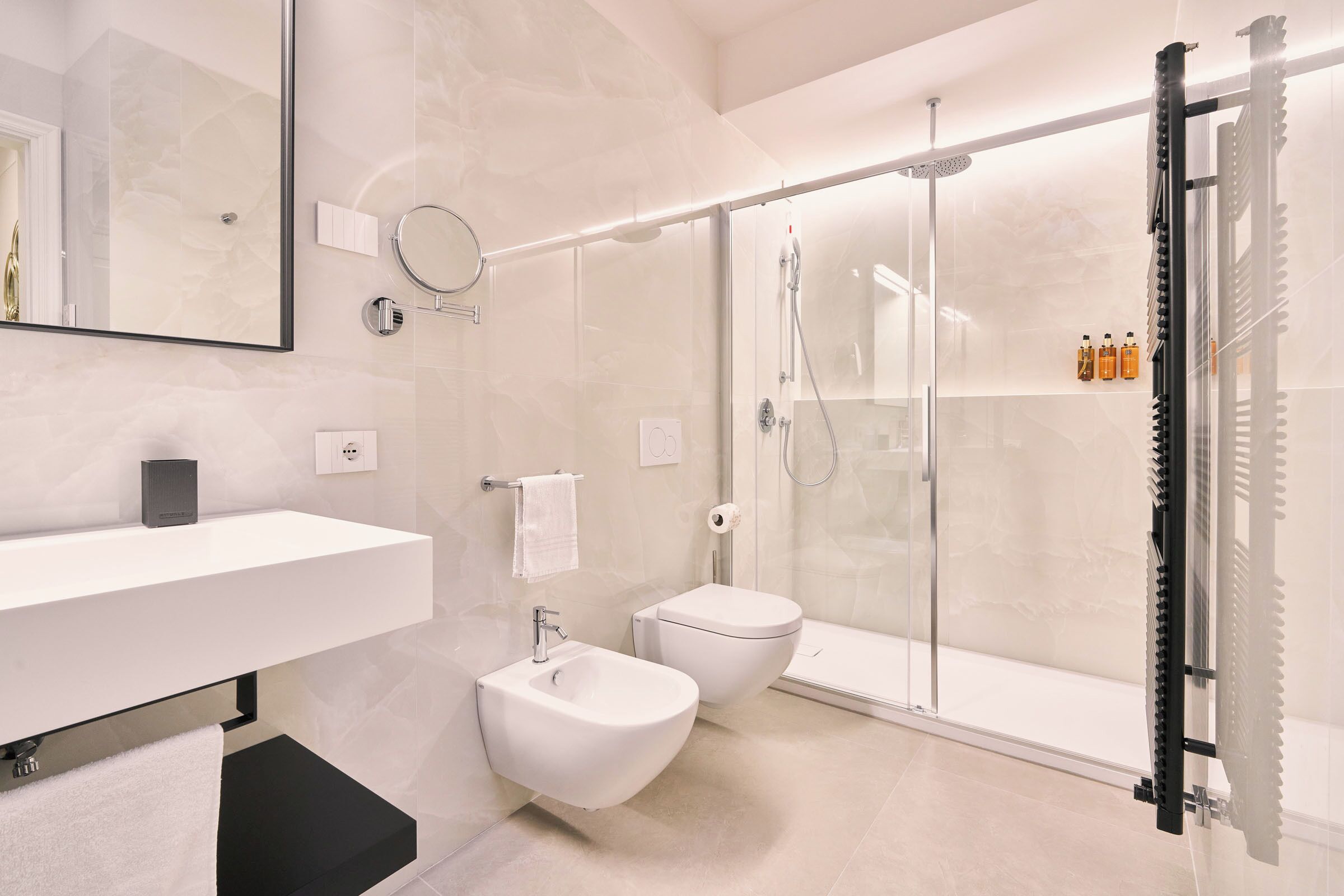 Un bagno moderno con box doccia in vetro, lavandino bianco e bidet.
