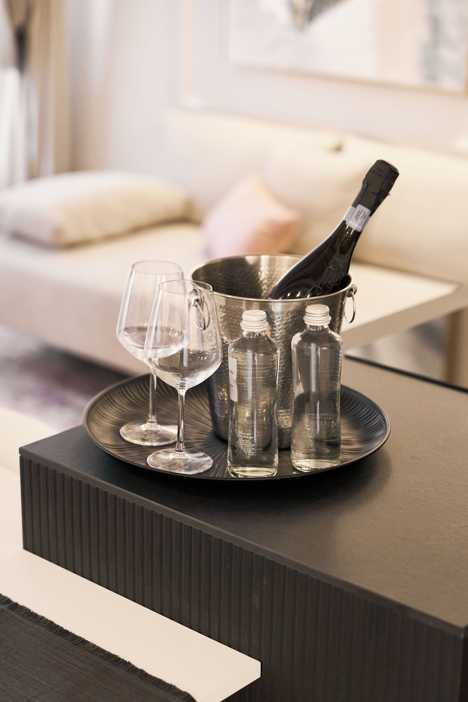 En bakke med champagne, to glas og to flasker på et bord.