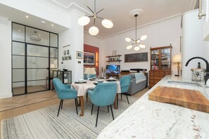 Un espace de vie moderne comprenant un coin repas, un canapé, un téléviseur et un îlot de cuisine.