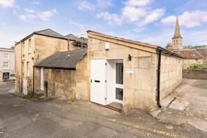 A stone building with a white door, a small entrance, and a sign reading 'THE STUDIO.' - One Bedroom Retreat in Prime Location - Pass the Keys (Bath)