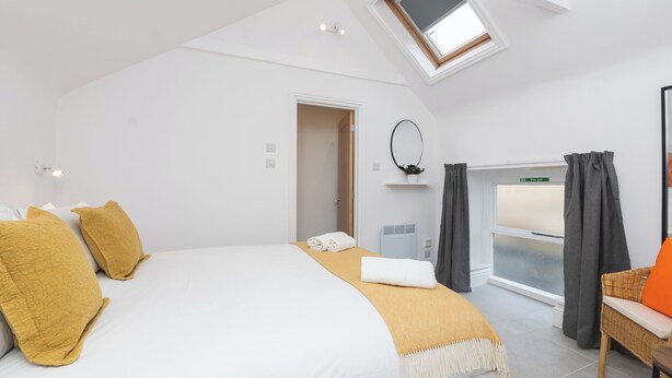 A bedroom with a bed, a skylight, a window, a mirror, and a chair. - One Bedroom Retreat in Prime Location - Pass the Keys (Bath)