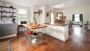 A modern kitchen with wooden cabinets, a central island, and a dining area with a view. - Georgia Grove (Atlanta)