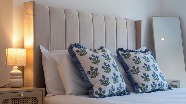 Een bed met twee kussens, een bedlampje en een nachtkastje met lades.
