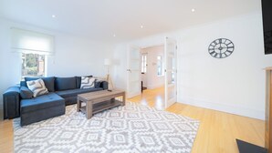 Een moderne woonkamer met een hoekbank, een salontafel en een kamerbreed tapijt met dessin.