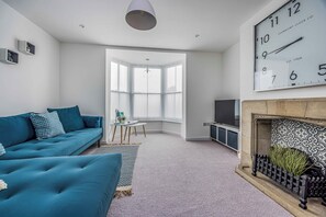 A modern living room with a sofa, a fireplace, a television, and a large window. - Modern Seaside Flat - Pass the Keys (Bognor Regis)