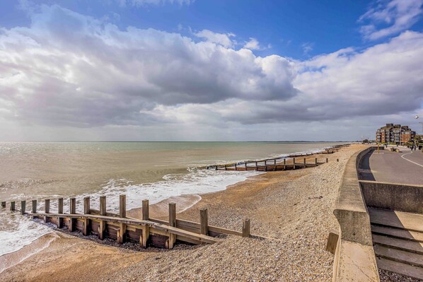 A beach with a wooden jetty, a concrete walkway, and a building in the background. - Modern Seaside Flat - Pass the Keys (Bognor Regis)