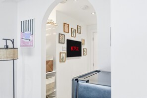 A hallway with a flat-screen TV displaying 'NETFLIX' and various framed pictures on the wall. - Dreamy Leeds Centre Retreat – Ideal for Couples - Pass the Keys (Leeds)