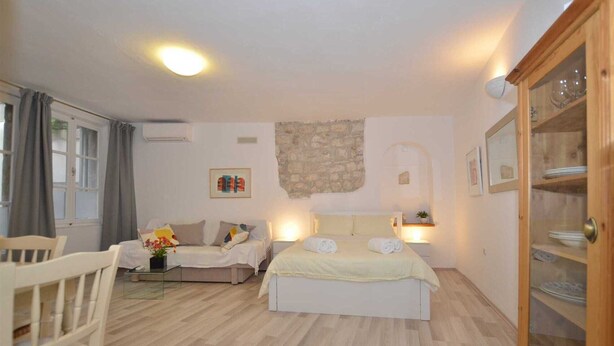 Een slaapkamer met een bed, een bank, een houten kast en een stenen muur.
