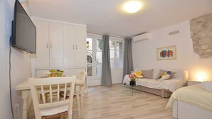 Een compacte woonruimte met een eethoek, kitchenette en slaapbank.
