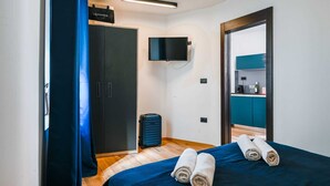 Una camera da letto con un letto, un armadio, una televisione e un bagno visibile attraverso una porta aperta.