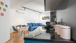 Una cucina moderna con isola blu, un'area pranzo con divano blu e un bancone con contenitori portaoggetti.
